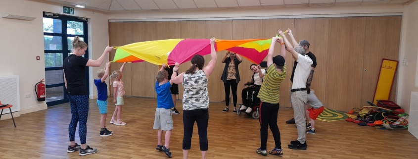 People lifting a play parachute in a sports hall